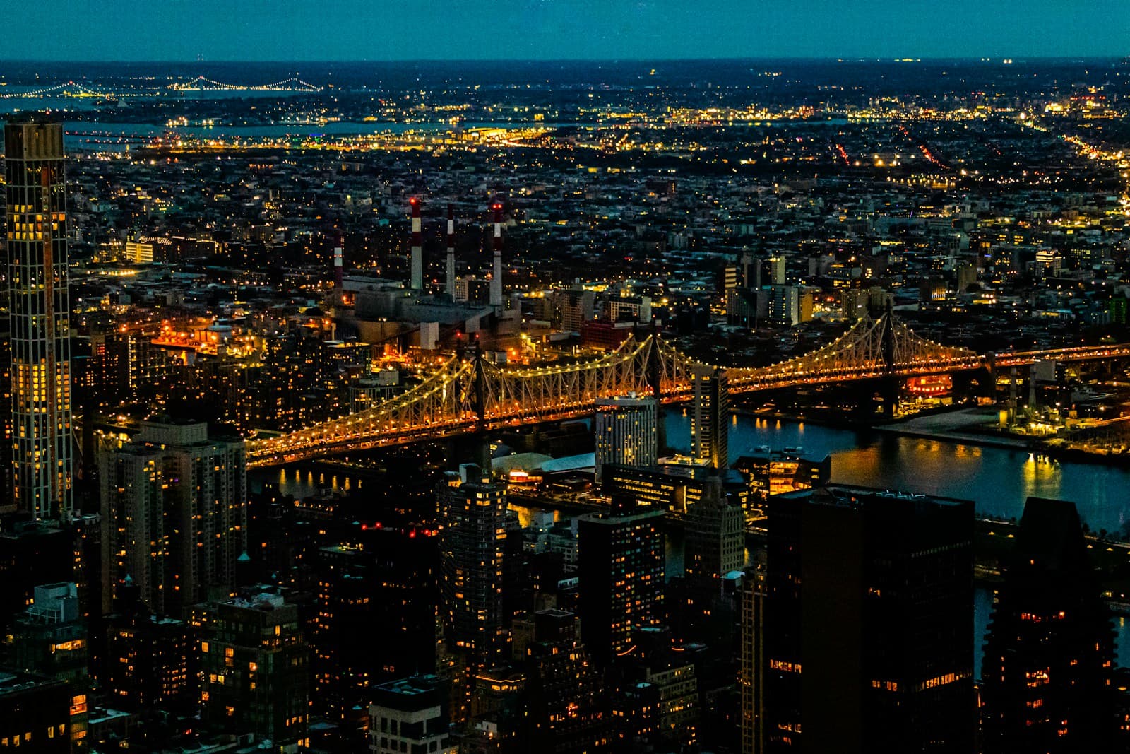 Aerial night view of New York City skyline with illuminated Brooklyn Bridge and Manhattan buildings