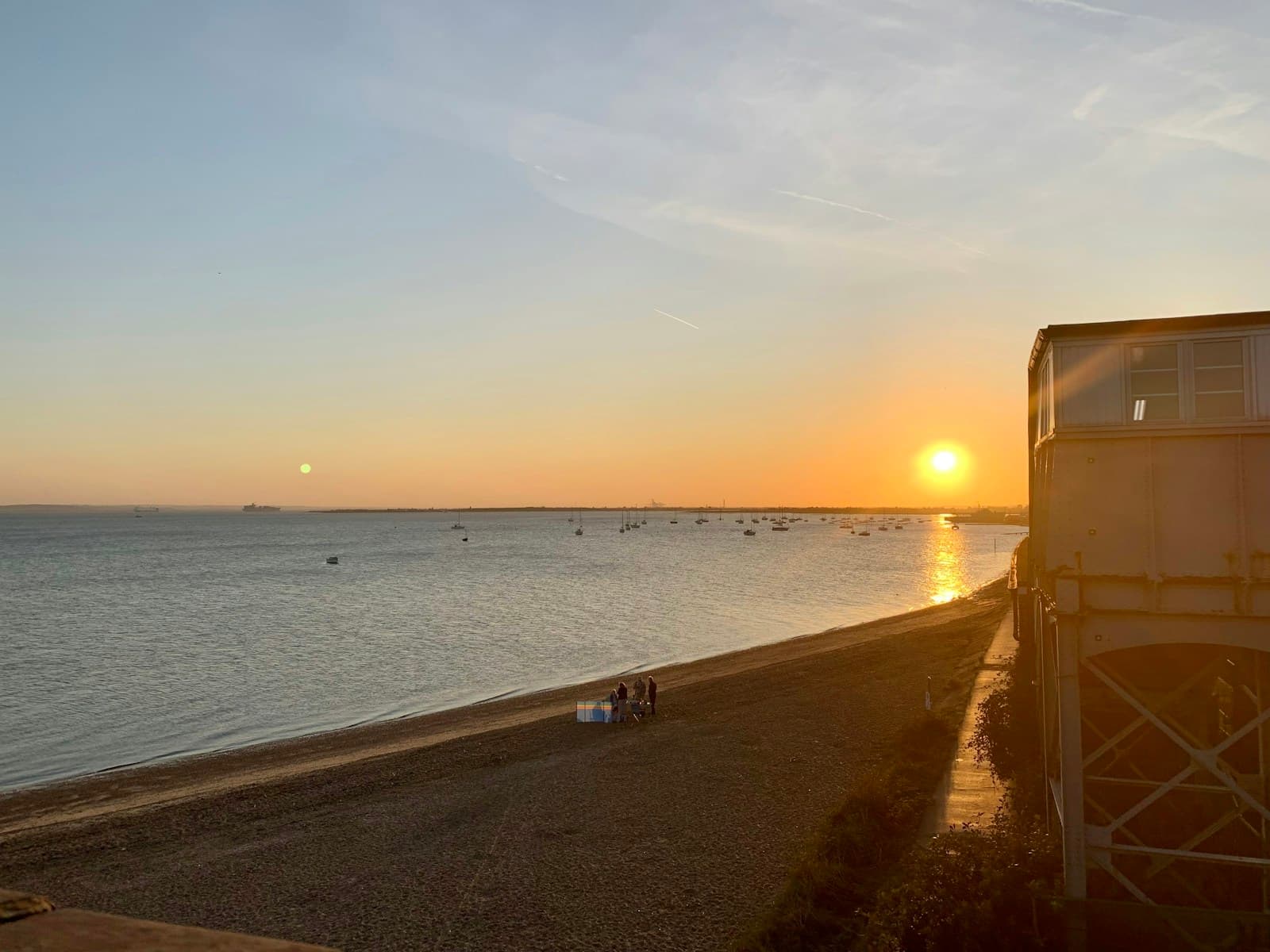 Sunset beach scene with lifeguard station, calm ocean, and golden sky reflecting on water