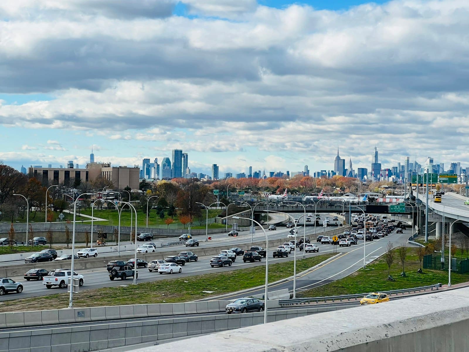 Highway with traffic leading toward city skyline with tall buildings under cloudy sky