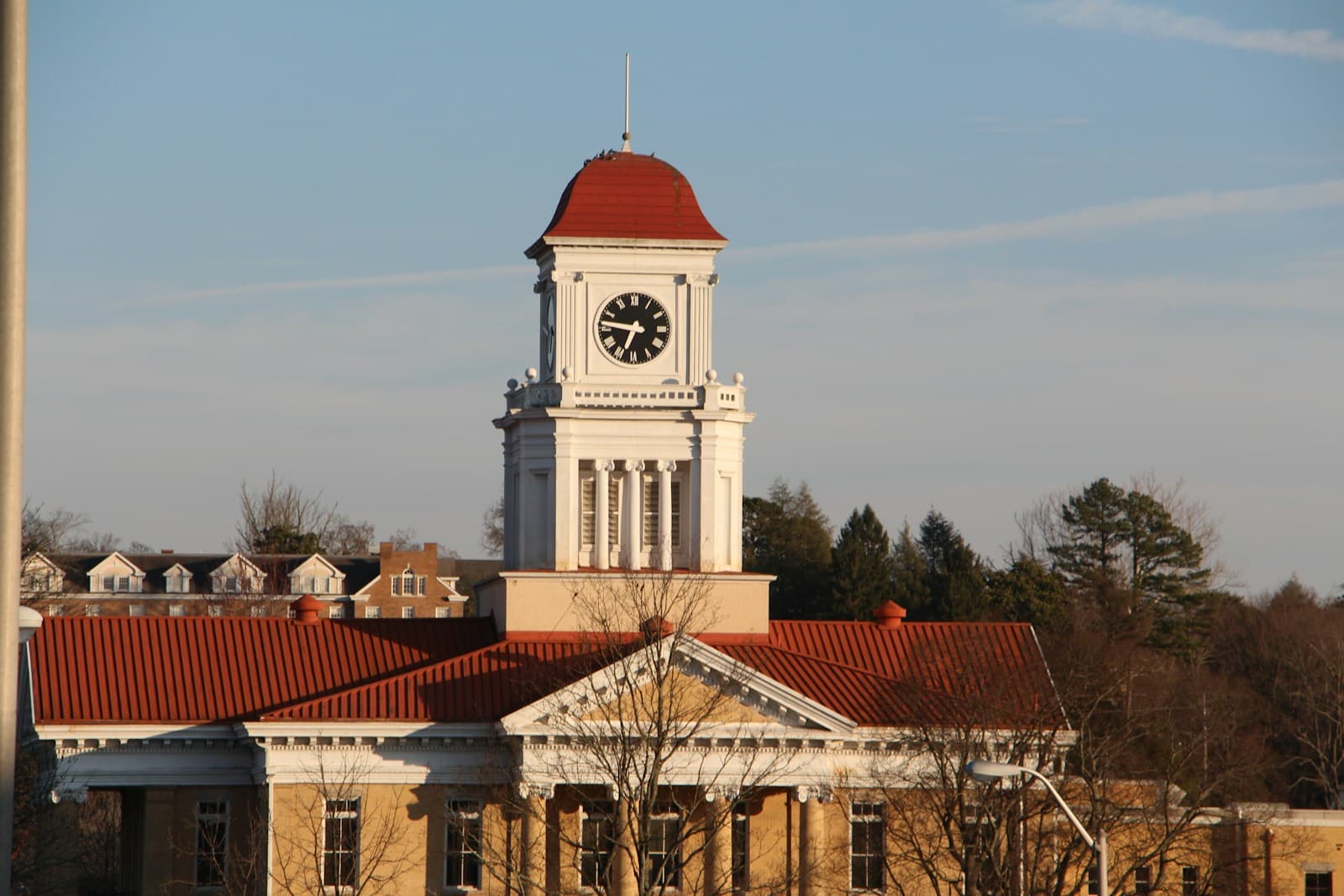 Historic brick building with white clock tower and red dome roof against blue sky