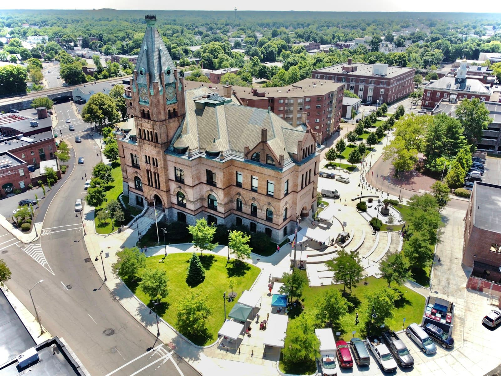 Aerial view of historic stone courthouse with clock tower surrounded by green lawn in small town center