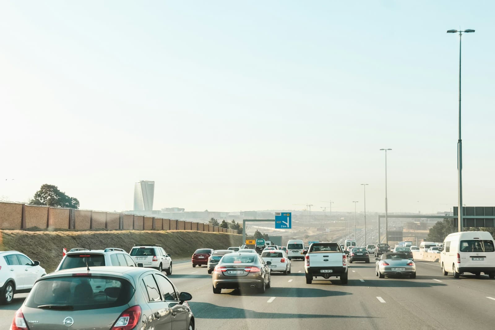 Multi-lane highway with traffic during daytime, showing cars, overpasses, and urban infrastructure